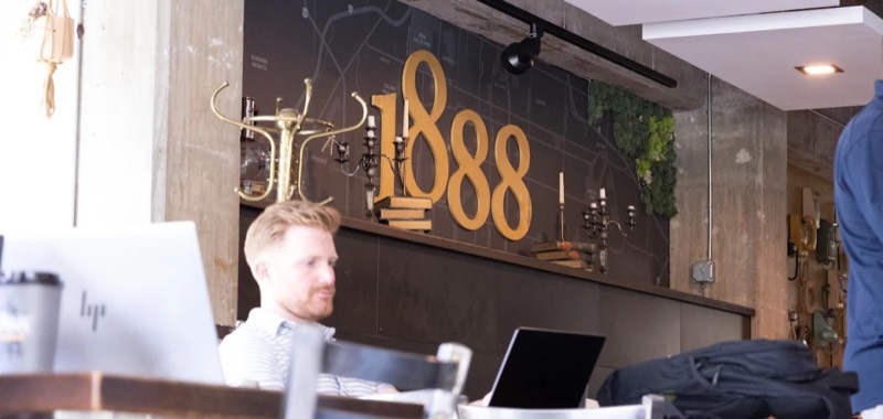 Working on a laptop in front of the 1888 wall